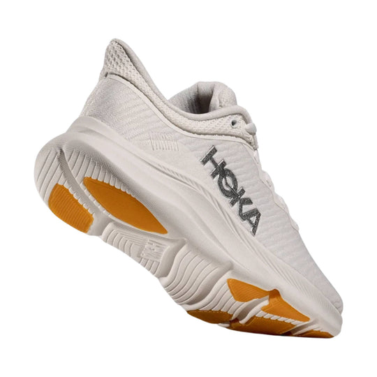 White low-top training shoe with orange outsole accents and a visible side logo