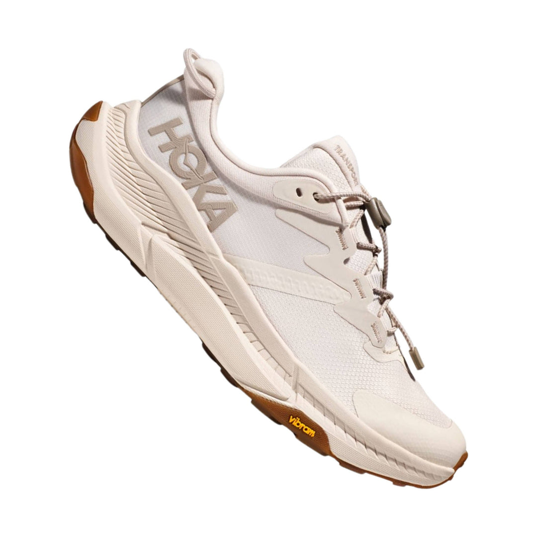 Off-white athletic shoe with bungee laces, textured mesh upper, and gum outsole
