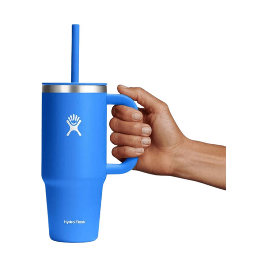 Blue insulated travel tumbler with straw and side handle, shown being held in a hand