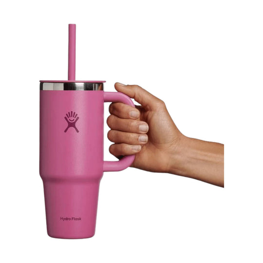 Pink handled travel tumbler with a straw and stainless rim, shown beside a hand