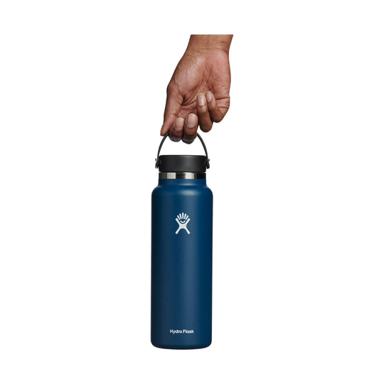 Dark blue insulated water bottle with black lid and carry handle, shown held by a hand