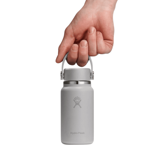 Small matte gray insulated water bottle with a carry handle, held by a hand