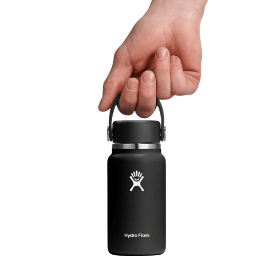 Black insulated water bottle with a carry loop, shown upright with a hand holding the cap