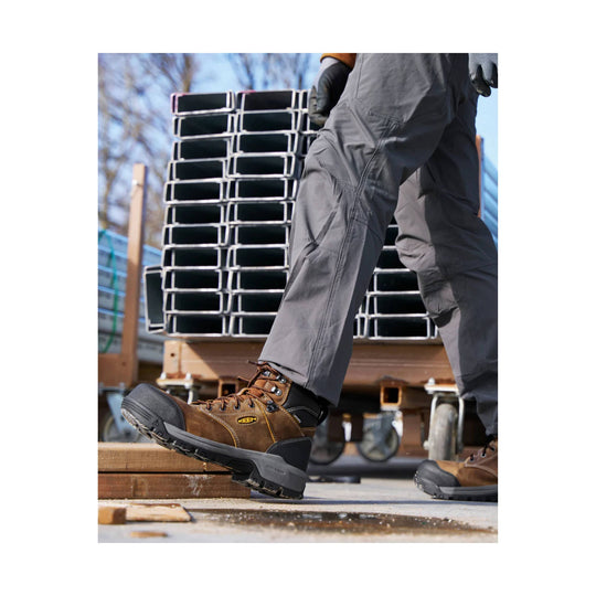 Brown lace-up work boot with black toe cap and black outsole, worn outdoors