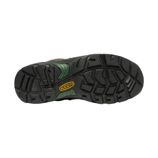 Black rugged boot outsole with deep tread and green accent inserts, showing a KEEN logo.