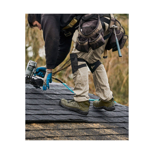 Olive and black waterproof work boots worn on a shingled roof