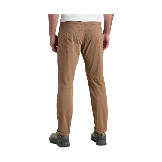 Tan straight-leg hiking pants with zippered thigh pockets and rolled cuffs, shown from the back.