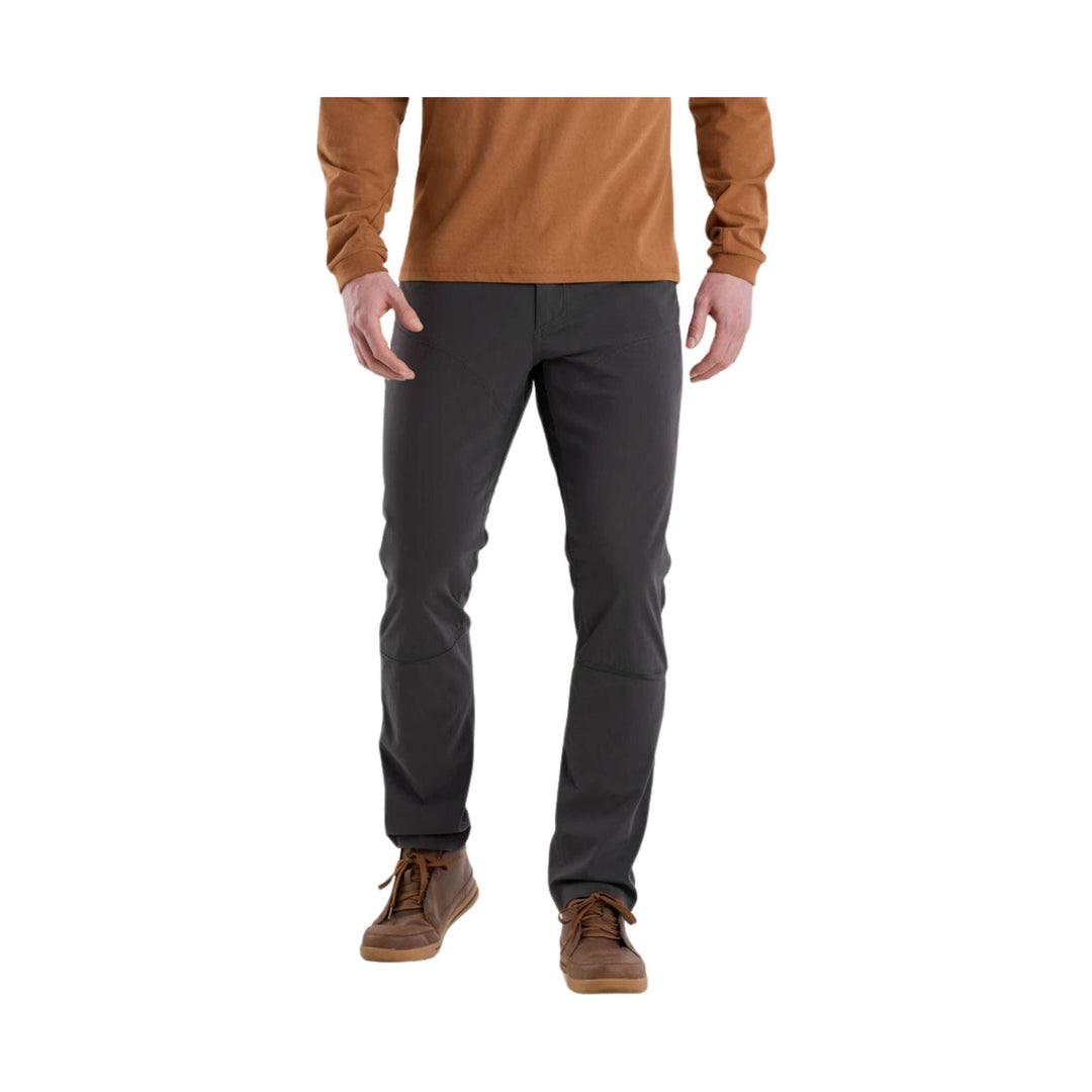 Black men’s outdoor pants with articulated knees and a straight fit, shown with brown hiking boots