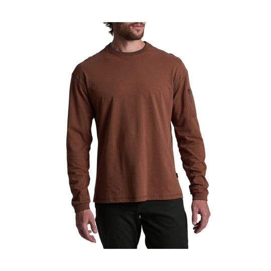 Rust-colored long-sleeve crewneck shirt with ribbed cuffs and a small sleeve logo