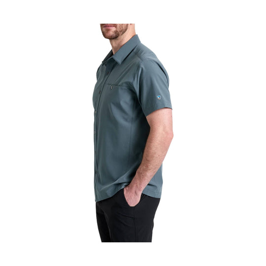 Short-sleeve button-up shirt in muted blue-gray with a chest pocket, worn with black pants