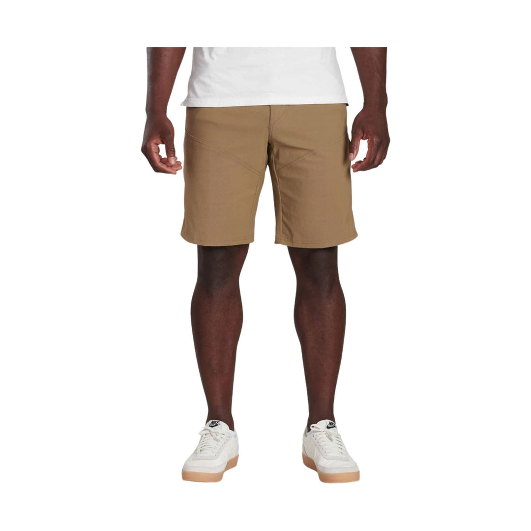 Tan men’s athletic shorts worn with a white T-shirt and white Nike sneakers on a model against a white background
