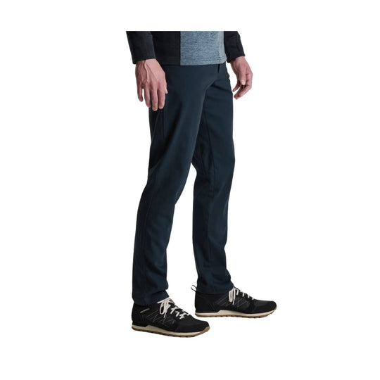 Black tapered pants with black hiking shoes and tan soles, shown from the waist down