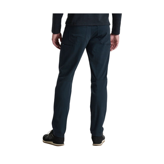 Dark navy tapered men’s pants with zipper pocket and cuffed hems, back view