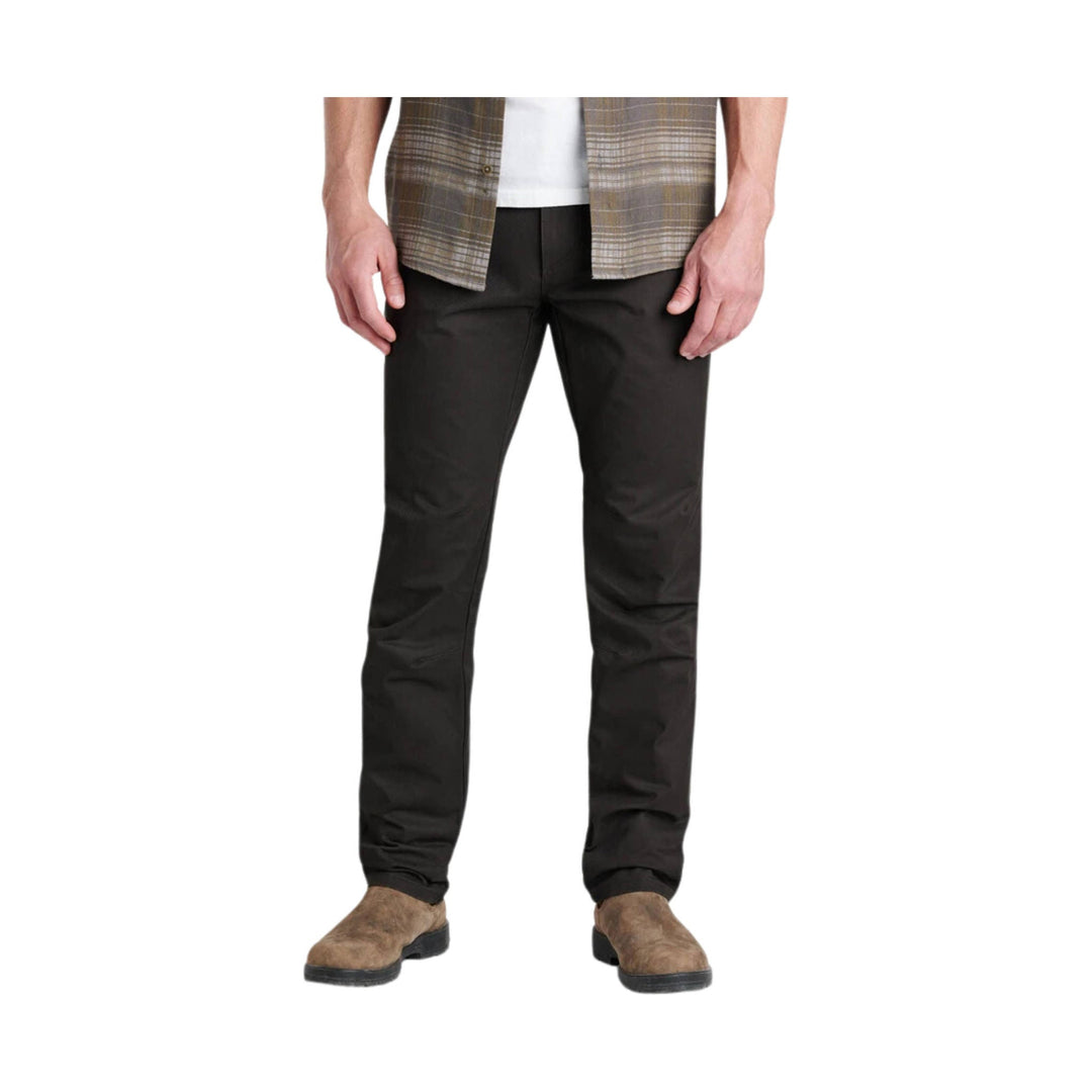 Person wearing black pants with a plaid shirt on a white background