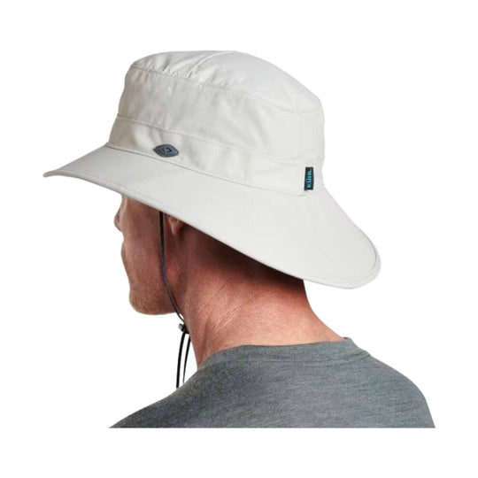 Light-colored wide-brim sun hat with chin cord, side logo tag, and rear neck flap
