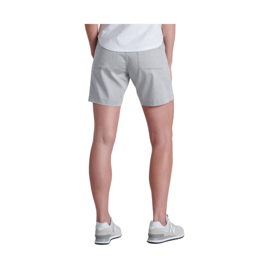 Light gray women’s athletic shorts shown from the back on a model, with patch back pockets and white sneakers