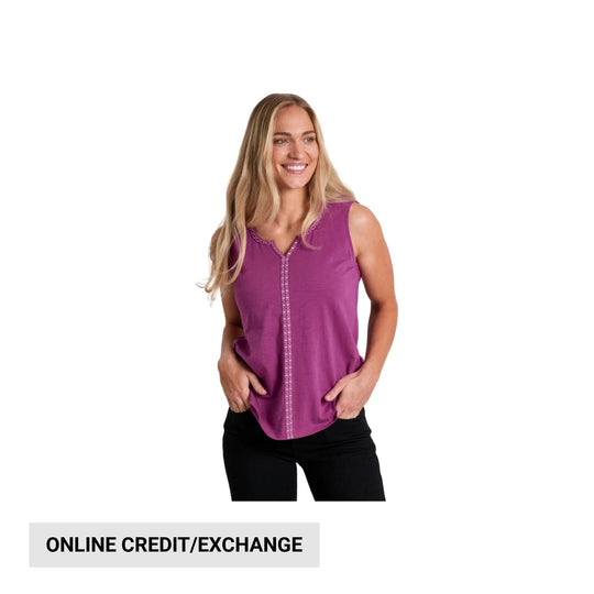 Woman wearing a sleeveless magenta top and black pants with hands in pockets