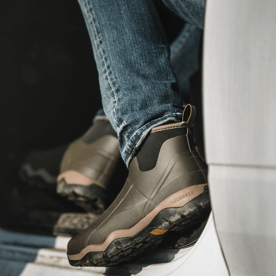 Olive and tan mid-height waterproof boots worn with jeans, shown from the side