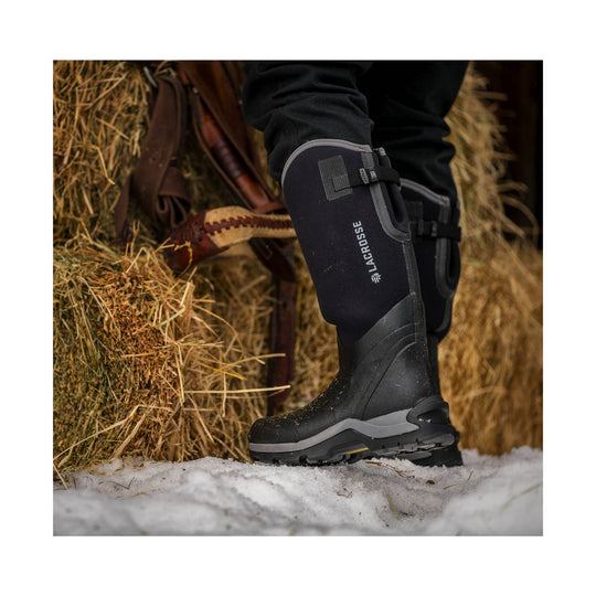 Black tall insulated boot with a gray sole and side strap, shown in snow