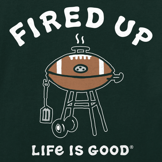 Graphic T-shirt design with a cartoon grill, spatula, and football under the text “FIRED UP” and “LIFE IS GOOD”.