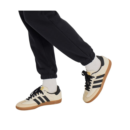 Black fleece joggers with elastic cuffs, shown with white socks and cream sneakers