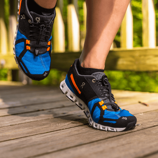 Blue and black athletic shoe with orange accents and a thick white outsole