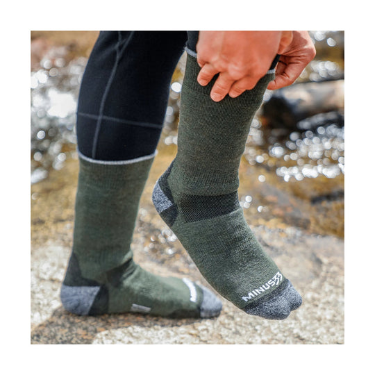 Olive green knee-high wool socks with gray toes and heels, shown on a person outdoors