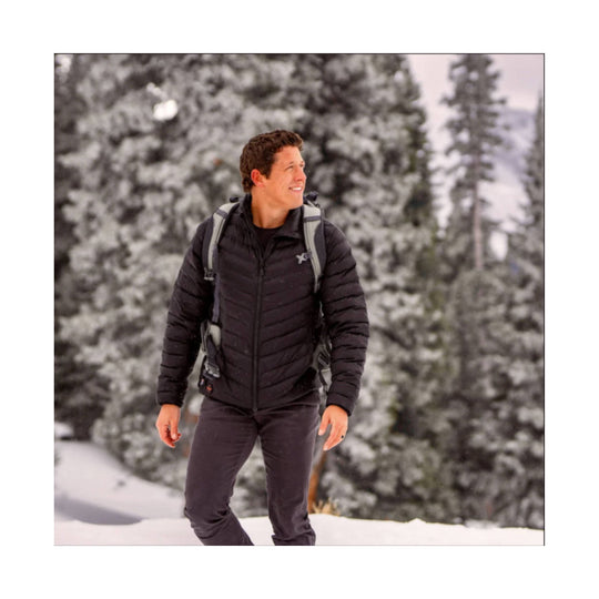 Black puffer jacket on a man standing in the snow with a backpack