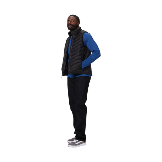 Black quilted puffer vest worn over a blue long-sleeve shirt, shown on a model with hands in pockets