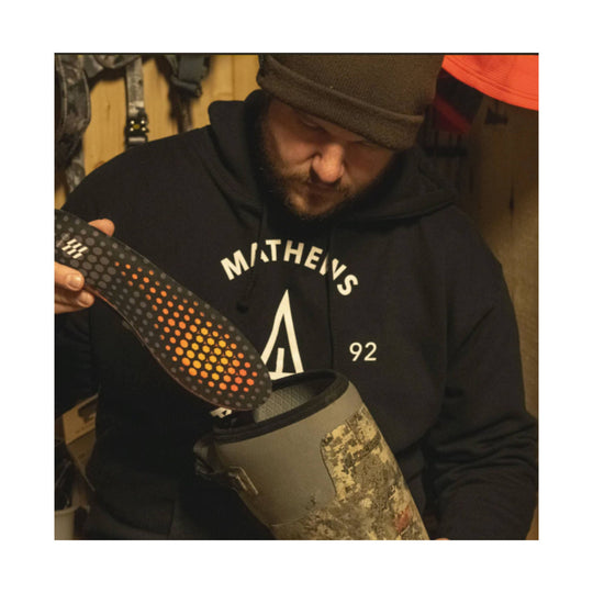 Heated insole with orange honeycomb-style heating zones beside a camo boot liner