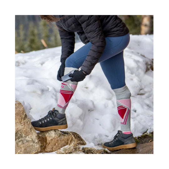 Gray and pink patterned knee-high socks worn with hiking boots in snow