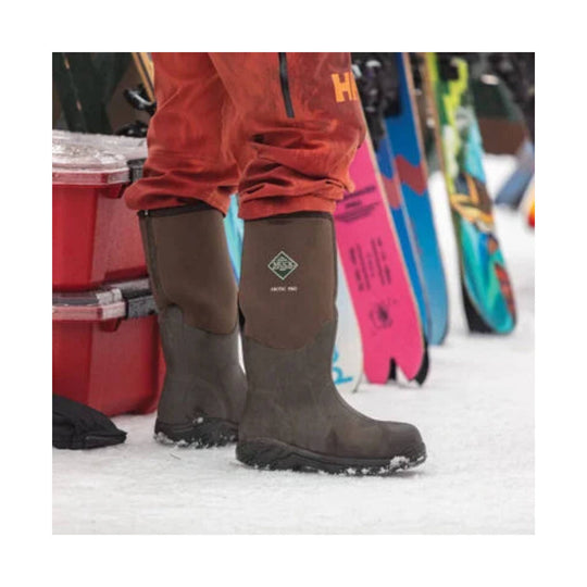 Brown knee-high insulated rubber snow boots on snow, with a small logo on the shaft