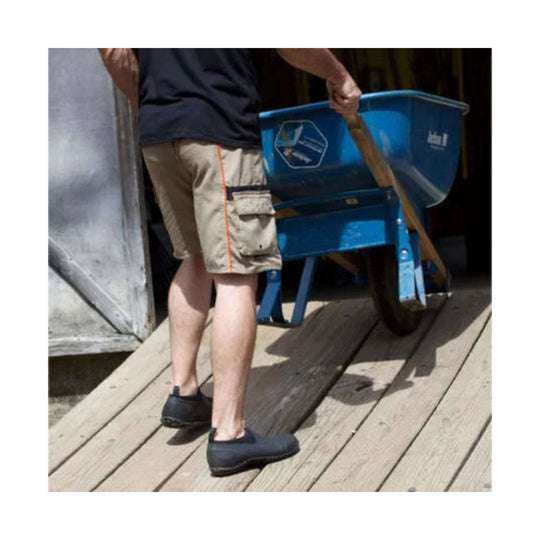 Black low slip-on garden boots worn with shorts on a wooden ramp