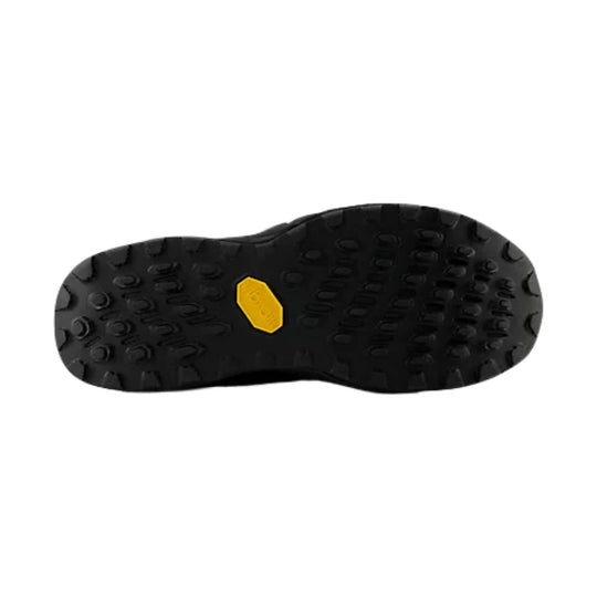 Black lugged trail shoe outsole with a yellow hexagonal logo insert