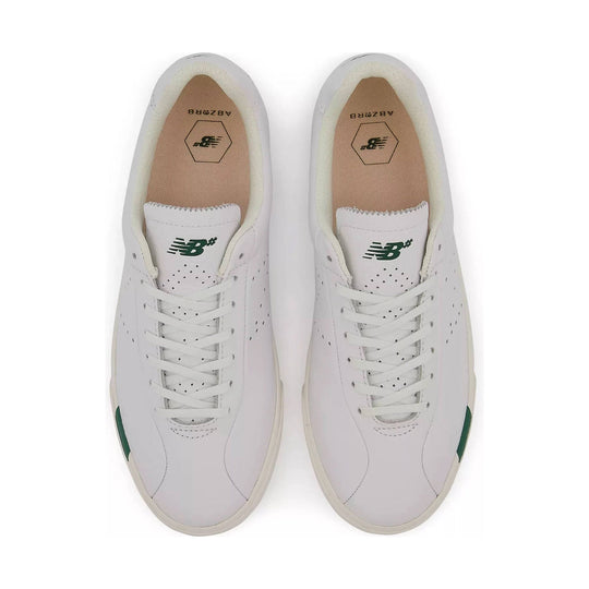 White low-top sneakers with green logos, perforated leather, and tan insoles, shown from above