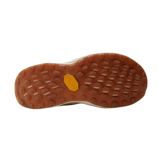 Trail shoe outsole with brown lugged rubber tread and a yellow Vibram logo