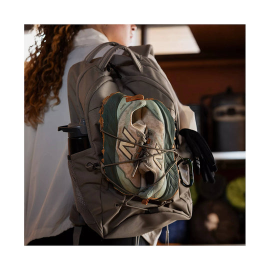Beige and dark green trail running shoe strapped to a gray backpack