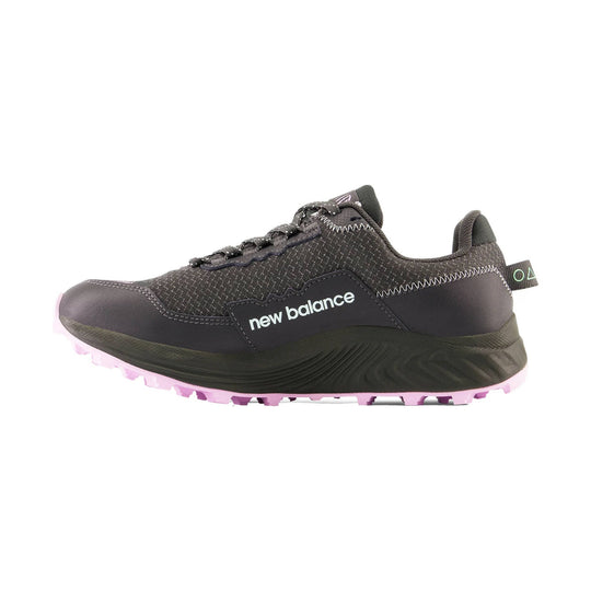 Dark trail running shoe with black upper, speckled knit collar, white New Balance side logo, and pink lugged outsole