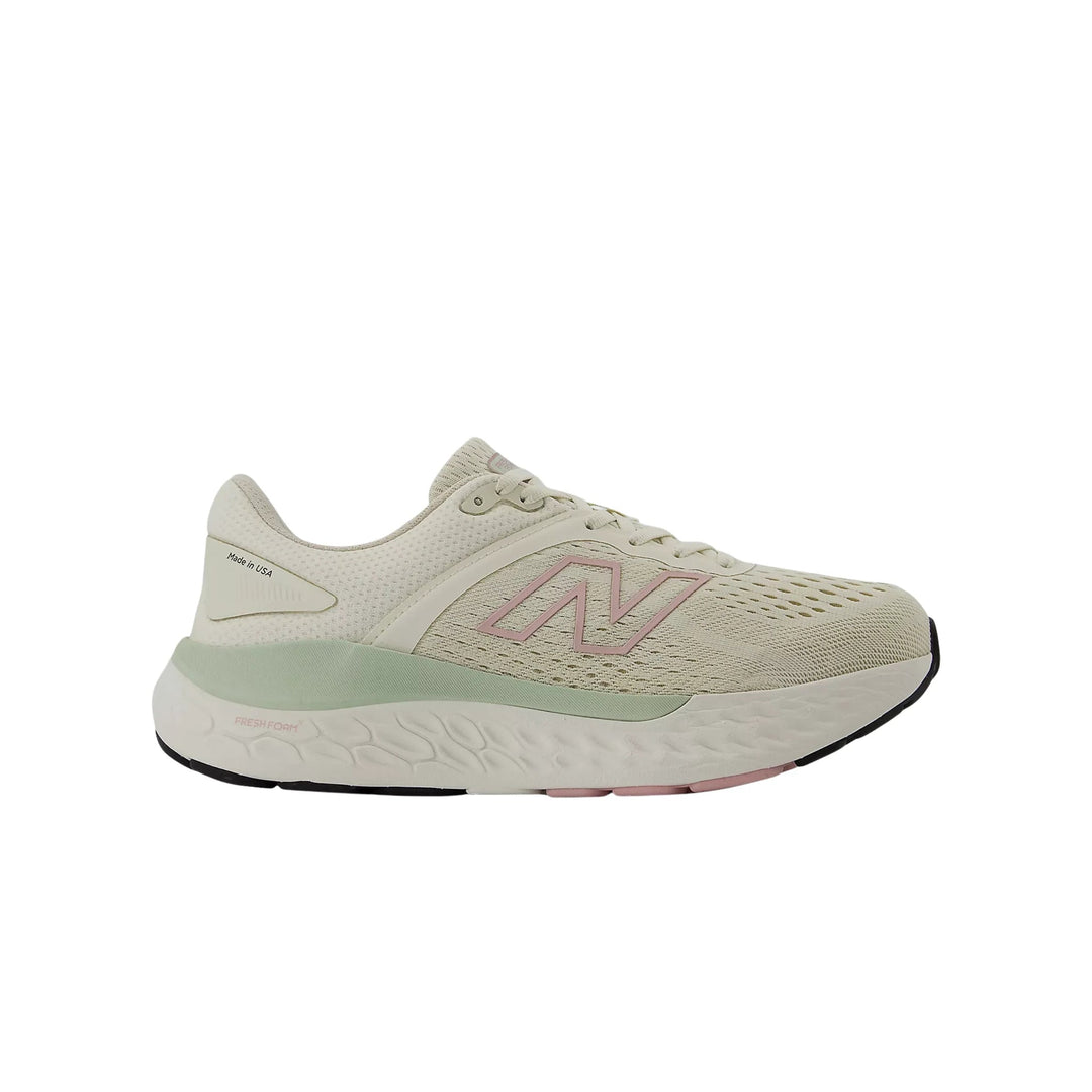 Cream running shoe in side view with pink logo and mint midsole, showing "Made in USA" text