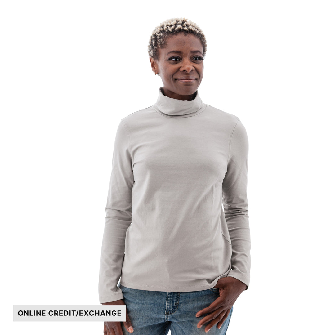 Woman wearing a light gray long-sleeve turtleneck and jeans