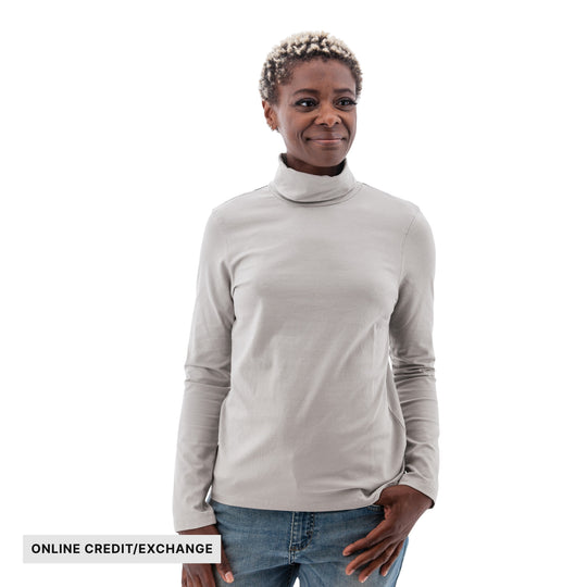 Woman wearing a light gray long-sleeve turtleneck and jeans