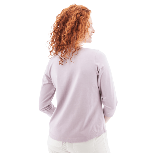 Woman wearing a light lavender long-sleeve top, shown from the back
