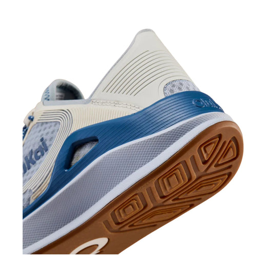 Blue and white athletic shoe shown from below, with a tan gum outsole and textured side panels