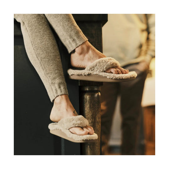 Beige fuzzy slide sandals worn with gray pants
