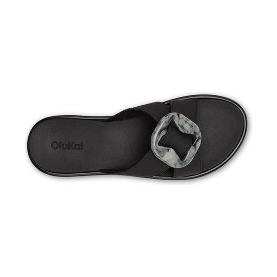 Black slide sandal with a marbled square buckle and visible OluKai logo on the insole