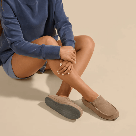 Tan suede slip-on moccasin-style shoes with stitched seams and thick rubber soles