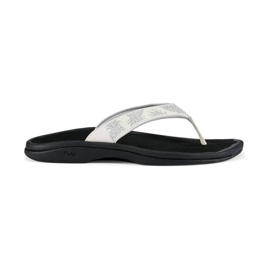 White thong sandal with a black footbed and floral-patterned strap, shown in side view