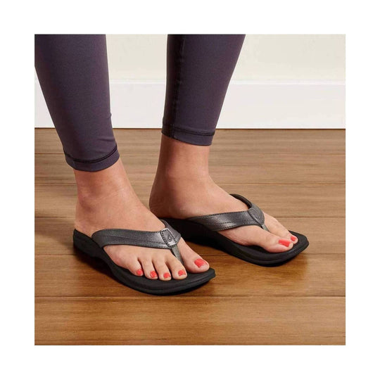Black thong sandals with gray straps and cushioned soles, worn with dark leggings