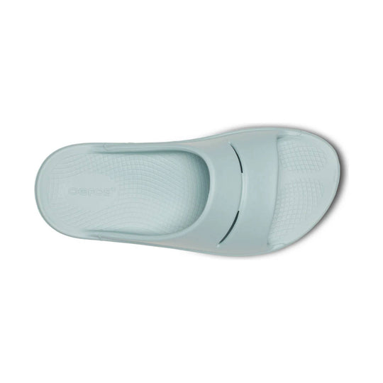 Light blue slide sandal seen from the sole side, with textured footbed and embossed logo