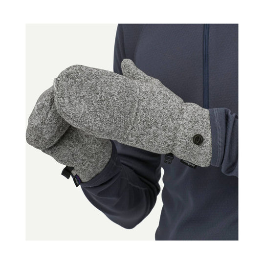 Gray fleece mittens with buttoned wrist cuffs on a model wearing a navy zip jacket